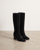 Botte ALLYE noir en daim posée au sol, studio mur blanc