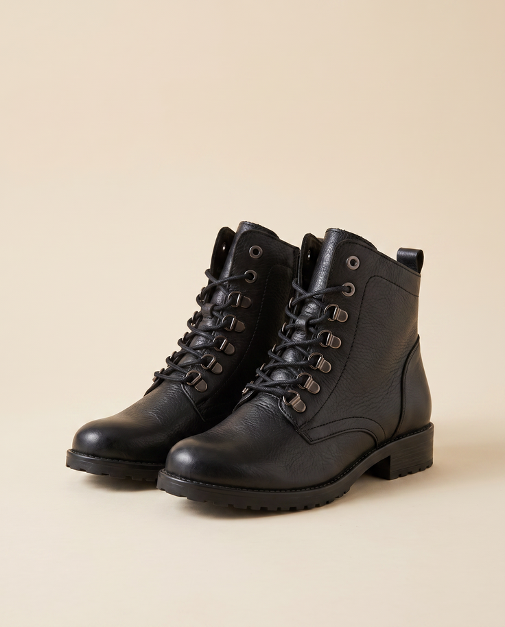 Boots AVI noir debout sur fond beige