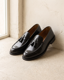 Mocassin EZRA noir posé sur sol béton clair, mur enduit crème