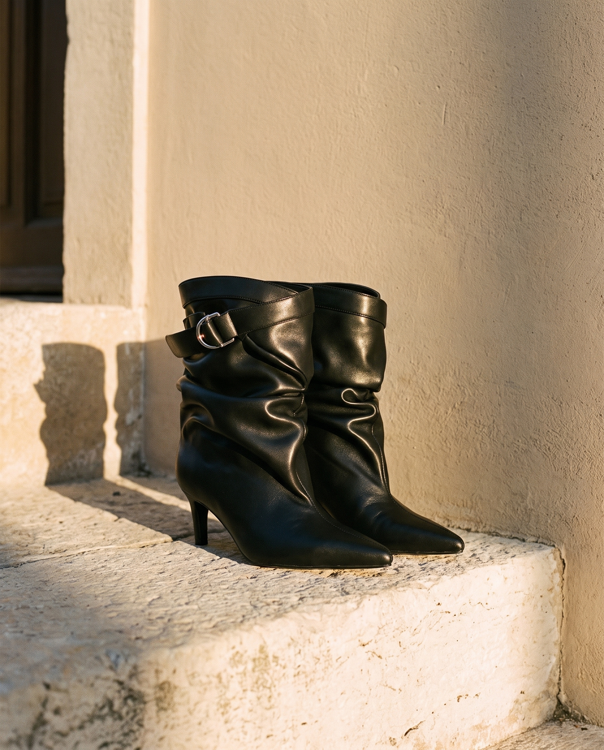 Paire de boots IDA noires posée sur une marche en pierre — A by André