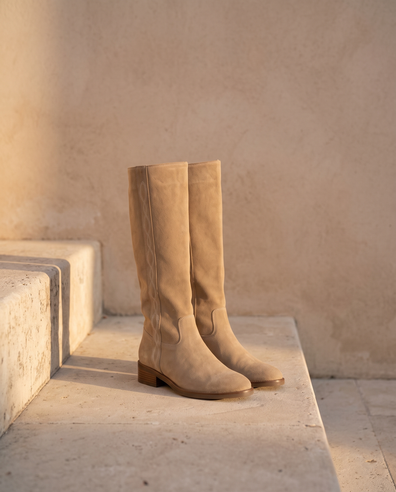 Paire de bottes INGRID sable en suède posée sur une marche en pierre — André