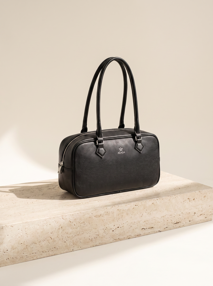 Sac bowling Noélie noir posé sur une marche en pierre de travertin, fond ivoire